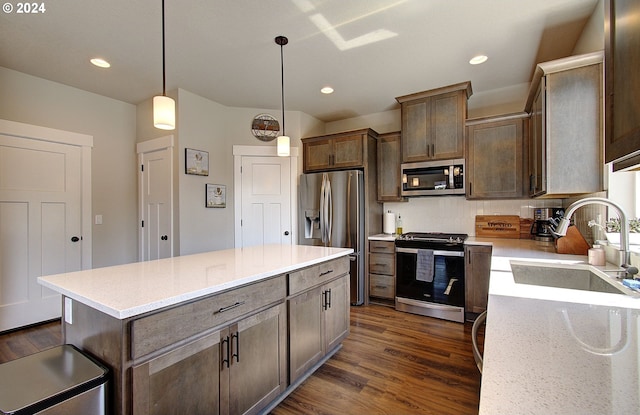 kitchen featuring appliances with stainless steel finishes, decorative light fixtures, sink, dark hardwood / wood-style flooring, and a center island