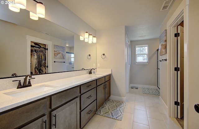 bathroom featuring walk in shower, vanity, and tile patterned flooring