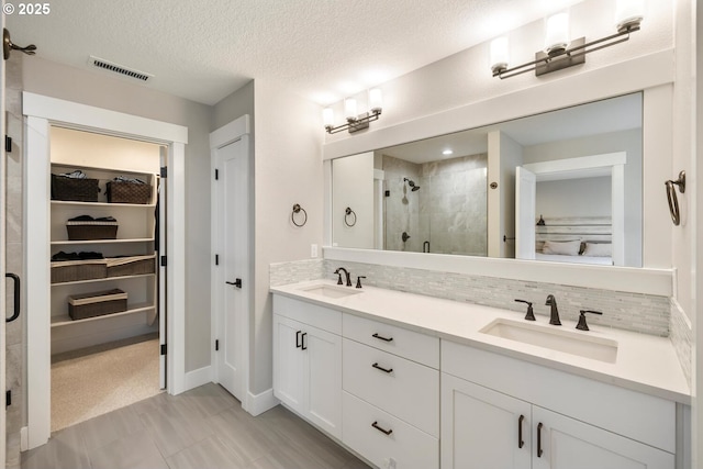 bathroom with tasteful backsplash, vanity, a textured ceiling, and walk in shower