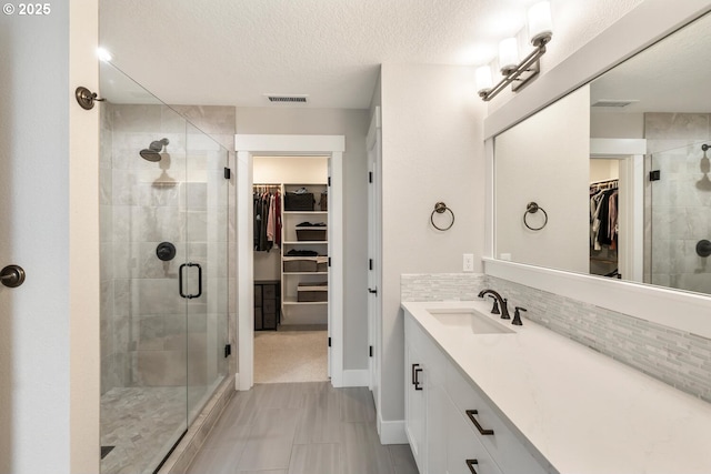 bathroom featuring tasteful backsplash, vanity, a textured ceiling, and walk in shower