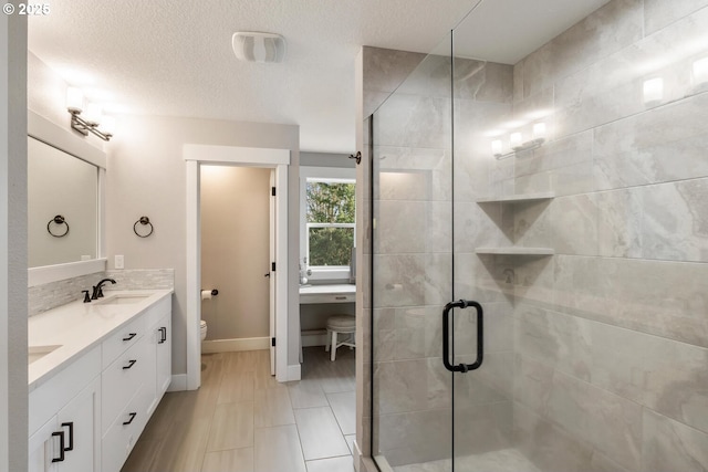 bathroom featuring vanity, a textured ceiling, toilet, and walk in shower