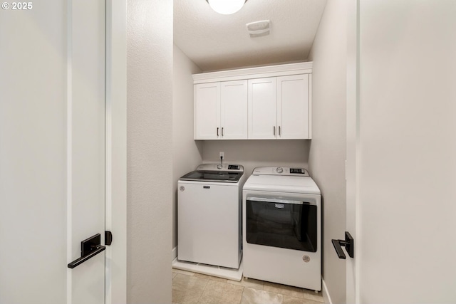 washroom featuring washer and clothes dryer, cabinets, and a textured ceiling