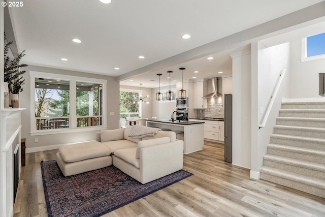 living room featuring a chandelier, sink, and light hardwood / wood-style flooring