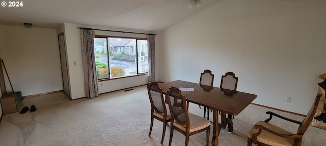 dining room with light colored carpet and lofted ceiling