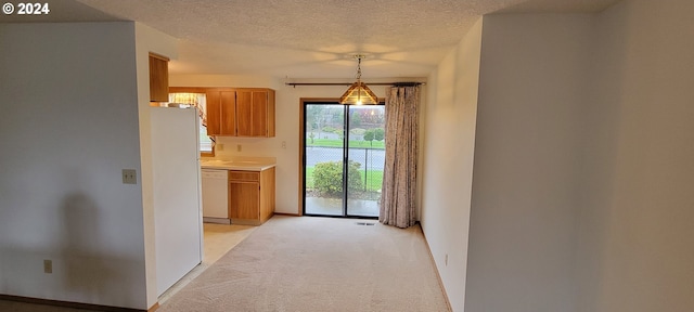 kitchen featuring light carpet, white dishwasher, hanging light fixtures, and a textured ceiling