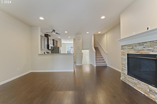 unfurnished living room with a fireplace, ceiling fan, and dark hardwood / wood-style flooring