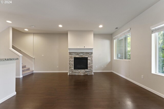 unfurnished living room featuring a wealth of natural light, dark hardwood / wood-style flooring, and a fireplace