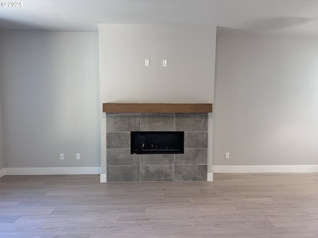 unfurnished living room with a tile fireplace and light hardwood / wood-style flooring