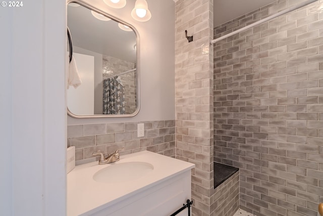 bathroom featuring a tile shower, vanity, and tile walls