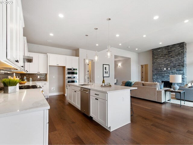 kitchen featuring stainless steel appliances, dark hardwood / wood-style floors, white cabinets, and a kitchen island with sink