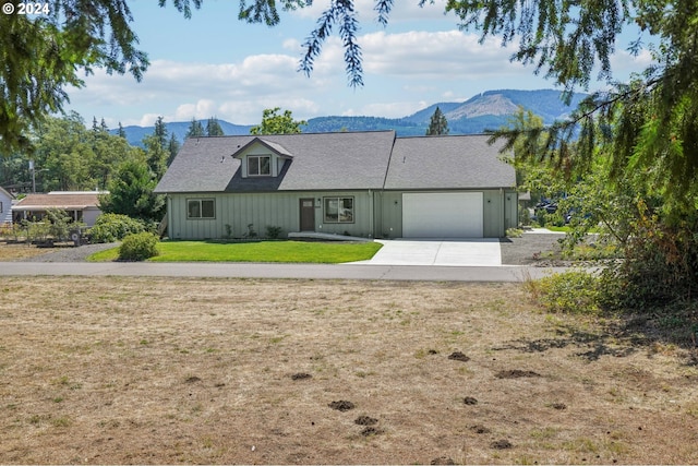 view of front of house featuring driveway, an attached garage, a mountain view, board and batten siding, and a front yard