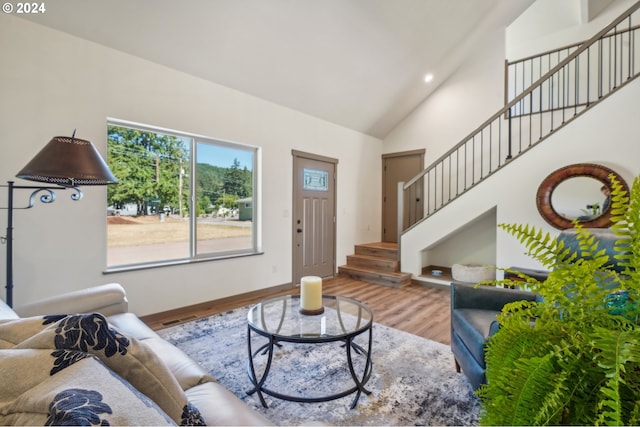 living room with high vaulted ceiling, recessed lighting, wood finished floors, baseboards, and stairs