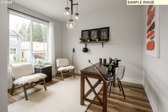 living room featuring a stone fireplace, wood-type flooring, and a high ceiling