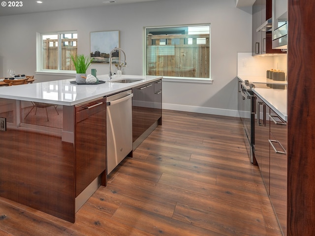 kitchen featuring sink, dark wood-type flooring, a center island with sink, exhaust hood, and appliances with stainless steel finishes