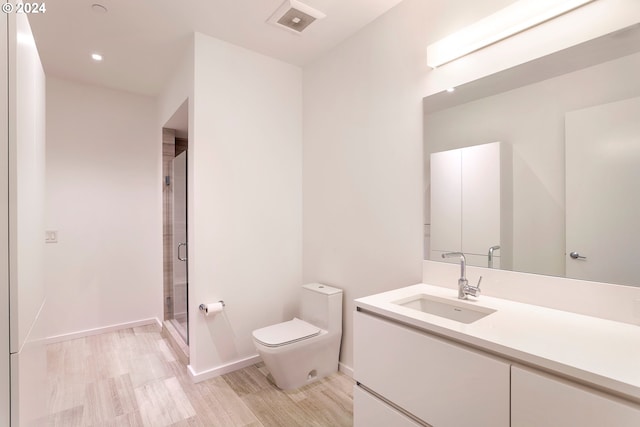 bathroom with hardwood / wood-style flooring, a shower with shower door, vanity, and toilet