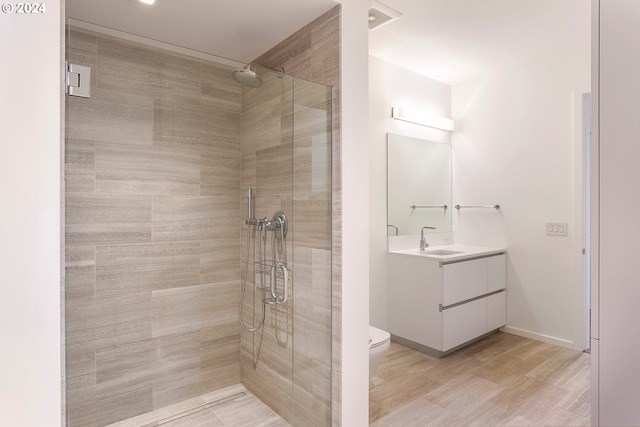 bathroom with wood-type flooring, vanity, a shower with door, and toilet