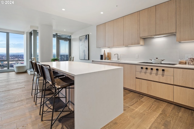 kitchen featuring a kitchen breakfast bar, gas cooktop, modern cabinets, and light brown cabinets