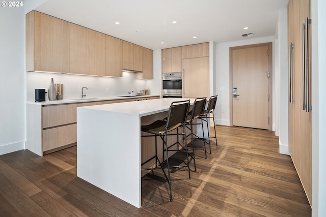 kitchen with light brown cabinets, a sink, dark wood-type flooring, black electric stovetop, and modern cabinets