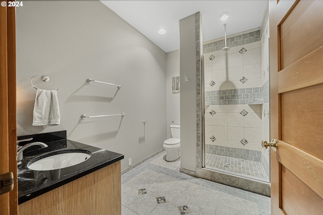 bathroom with tile patterned floors, toilet, a tile shower, and vanity