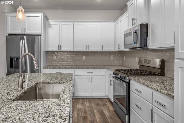 kitchen with white cabinets, appliances with stainless steel finishes, decorative light fixtures, and dark wood-type flooring