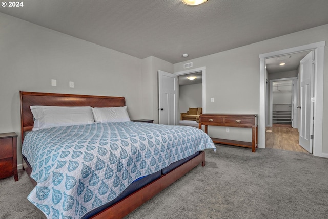 bedroom featuring a textured ceiling, light colored carpet, and a spacious closet