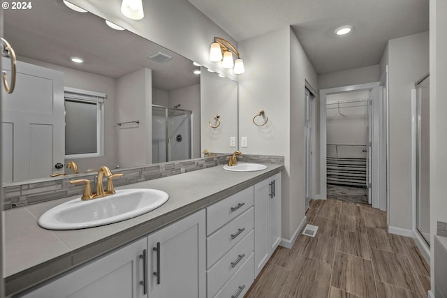 bathroom with decorative backsplash, vanity, and a shower with door