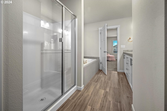 bathroom with a stall shower, wood tiled floor, a garden tub, and vanity