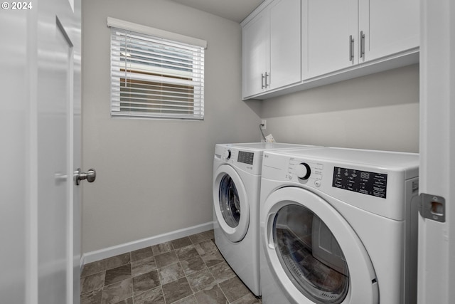 clothes washing area with cabinets and washing machine and clothes dryer