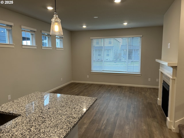 interior space featuring dark wood-style floors, hanging light fixtures, baseboards, and light stone countertops