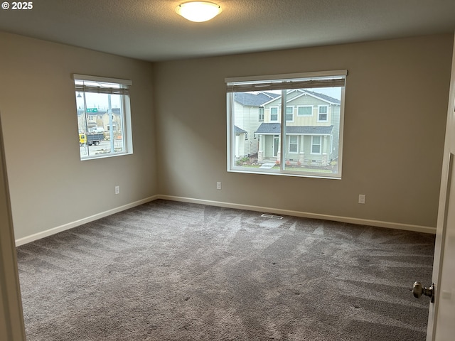 carpeted spare room featuring baseboards and a textured ceiling