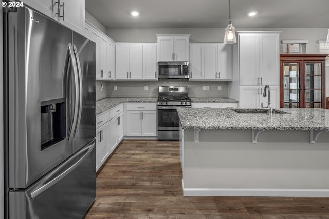 kitchen with white cabinets, stainless steel appliances, light stone counters, and hanging light fixtures