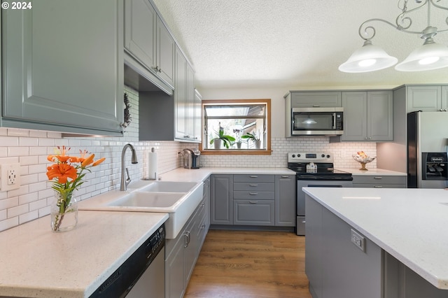 kitchen with pendant lighting, appliances with stainless steel finishes, sink, dark wood-type flooring, and decorative backsplash