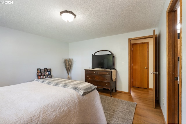 bedroom featuring light hardwood / wood-style floors and a textured ceiling