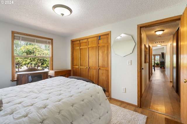 bedroom featuring hardwood / wood-style flooring, a textured ceiling, and a closet