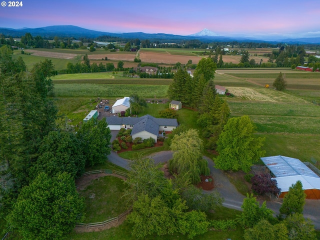 aerial view at dusk featuring a mountain view and a rural view