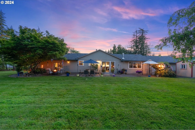 back house at dusk with a patio area and a yard