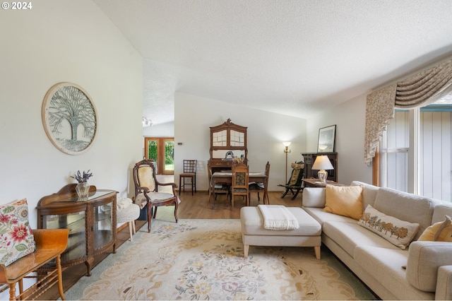 living room with hardwood / wood-style flooring, a textured ceiling, and lofted ceiling