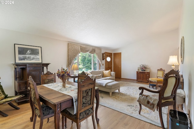 dining area featuring a textured ceiling and light hardwood / wood-style flooring