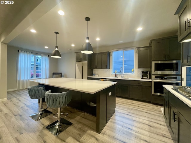 kitchen with tasteful backsplash, light countertops, a kitchen bar, appliances with stainless steel finishes, and a sink