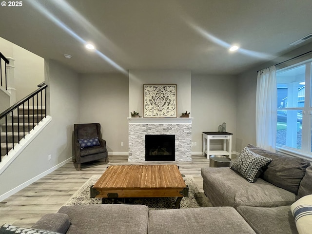 living room featuring stairway, baseboards, wood finished floors, and a fireplace