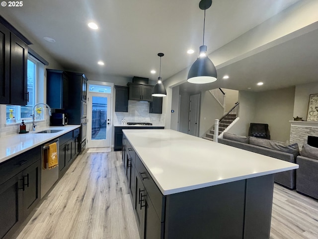 kitchen featuring stainless steel dishwasher, gas cooktop, light wood-type flooring, and a sink