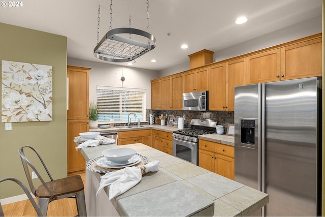 8844 NE Brentford Way, Hillsboro, OR 97006 - kitchen with decorative backsplash, appliances with stainless steel finishes, sink, tile countertops, and light hardwood / wood-style flooring