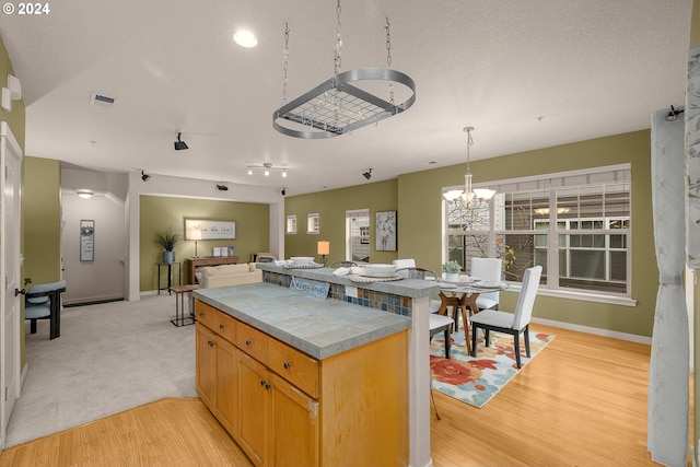 8844 NE Brentford Way, Hillsboro, OR 97006 - kitchen with light hardwood / wood-style flooring, pendant lighting, a textured ceiling, and a notable chandelier