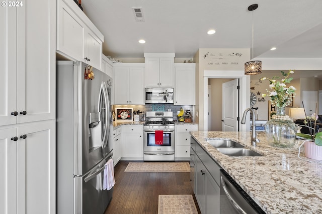 kitchen with stainless steel appliances, white cabinetry, sink, and pendant lighting