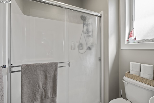 bathroom with toilet and a shower with door