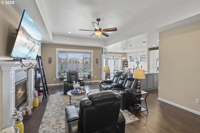 living room featuring a raised ceiling, dark hardwood / wood-style floors, and ceiling fan