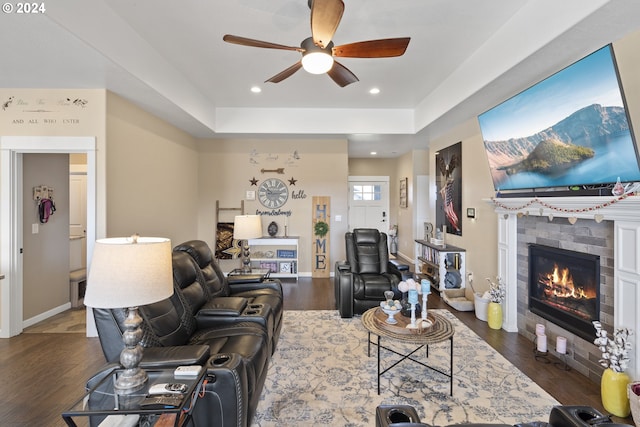 living room featuring dark hardwood / wood-style floors, ceiling fan, and a tray ceiling