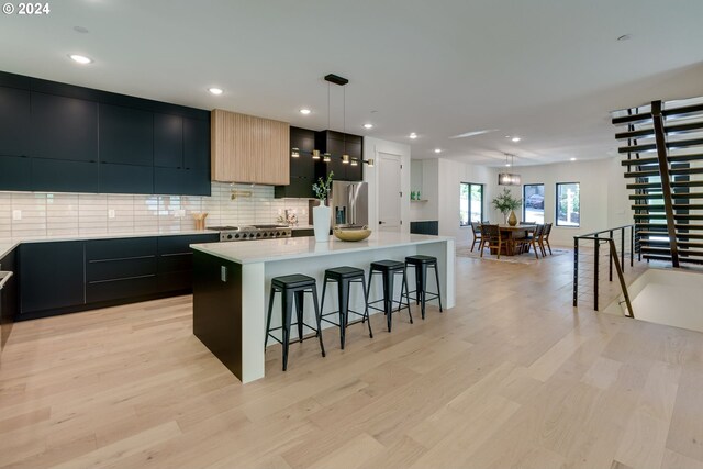 kitchen featuring a center island, stainless steel fridge, pendant lighting, light hardwood / wood-style floors, and a breakfast bar area