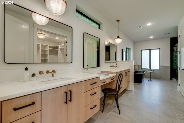 bathroom with a washtub, vanity, and tile patterned flooring