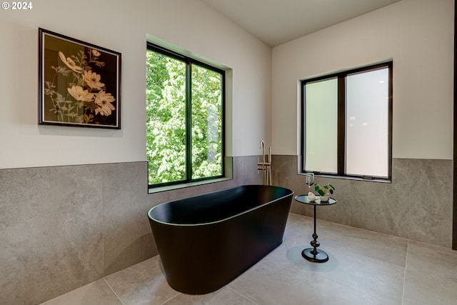 bathroom featuring tile patterned flooring, a washtub, and tile walls